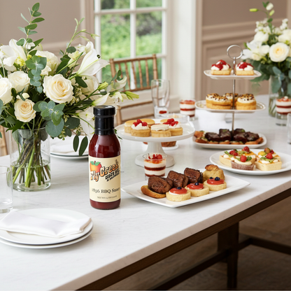 Table with assorted desserts, flowers, and a bottle of Big Creek Original BBQ Sauce.